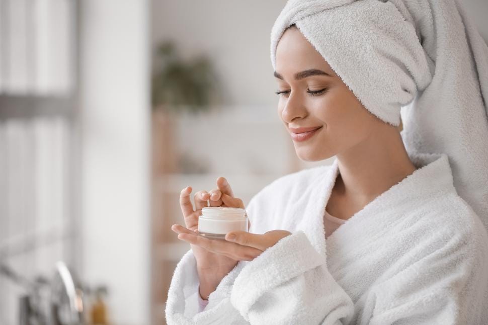 Woman applying skincare products in a calm, softly lit bathroom as part of an evening self-care routine