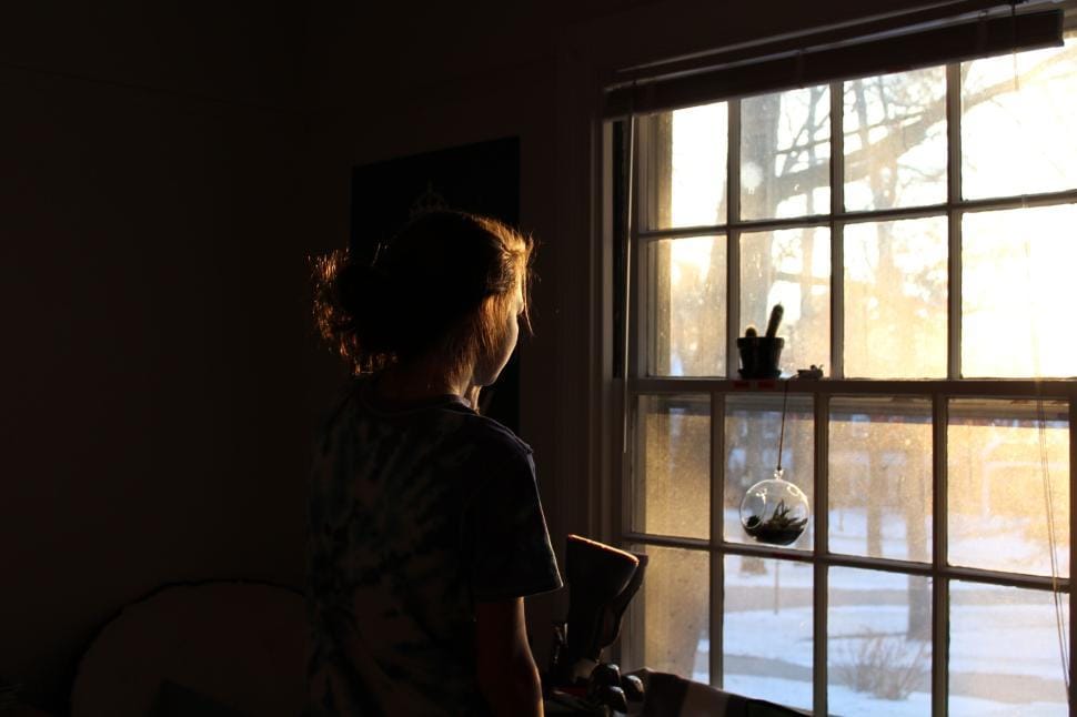 Person waking up and stretching near a sunlit window in the morning